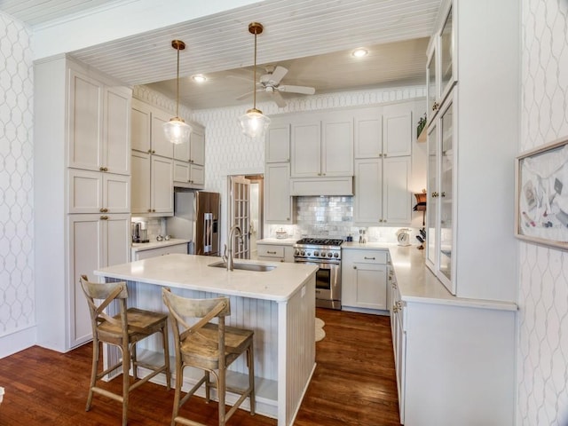 kitchen featuring sink, a kitchen island with sink, high end appliances, a kitchen bar, and decorative light fixtures