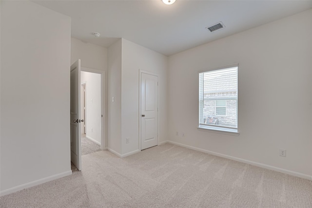 unfurnished bedroom featuring light colored carpet and a closet