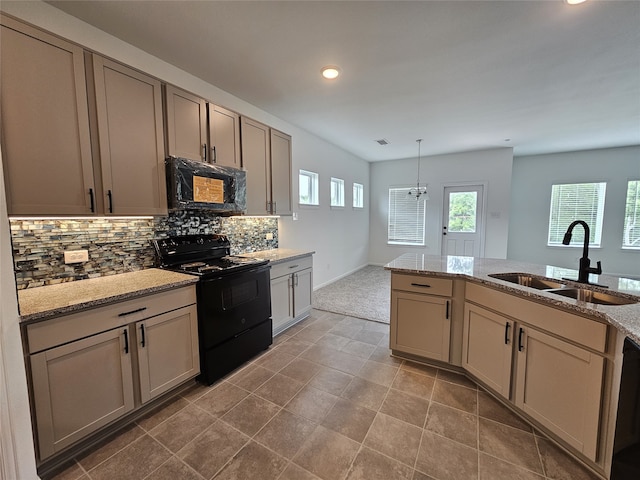 kitchen featuring sink, light stone counters, cream cabinets, black appliances, and decorative light fixtures