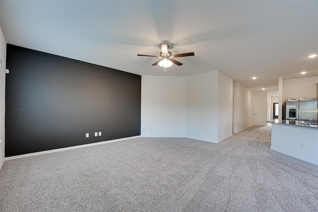 unfurnished living room with light colored carpet and ceiling fan