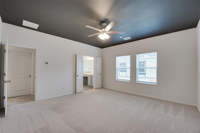 unfurnished bedroom featuring light carpet, connected bathroom, and ceiling fan