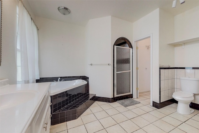 bathroom featuring vanity, tile patterned floors, tiled bath, and toilet