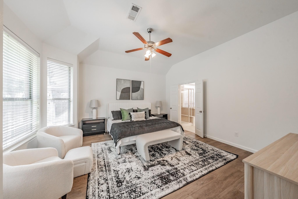 bedroom featuring hardwood / wood-style floors, lofted ceiling, connected bathroom, and ceiling fan