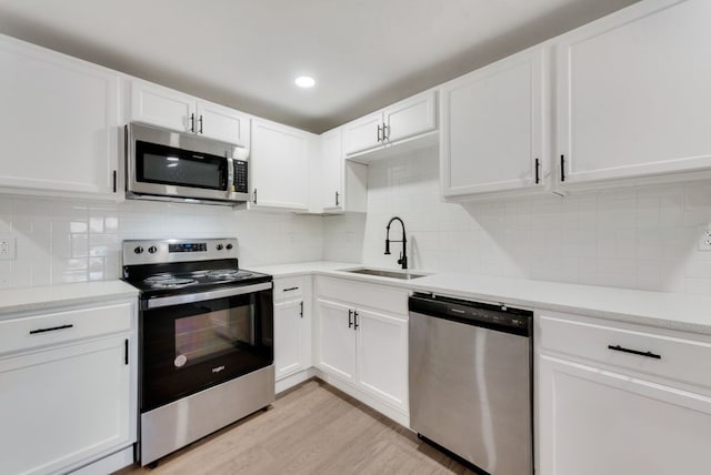 kitchen featuring tasteful backsplash, white cabinetry, appliances with stainless steel finishes, and sink