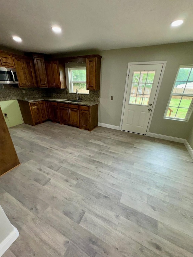 kitchen with sink, decorative backsplash, and light wood-type flooring