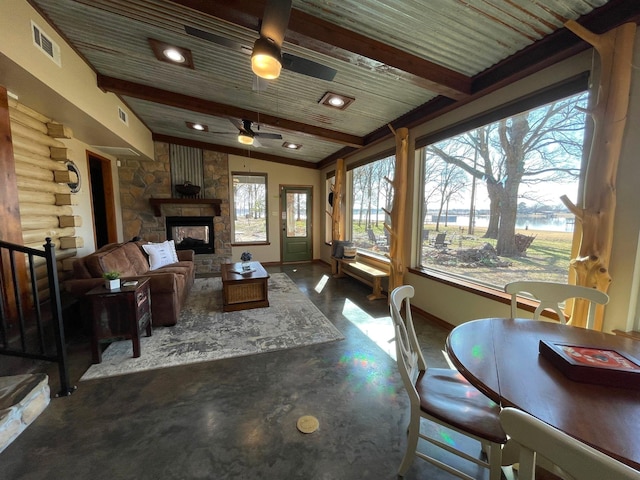 living room featuring ceiling fan, a wealth of natural light, a fireplace, and beam ceiling