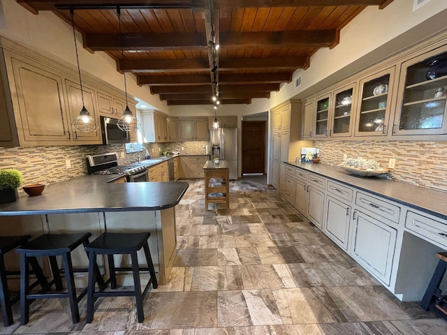 kitchen with hanging light fixtures, beam ceiling, stainless steel appliances, and backsplash