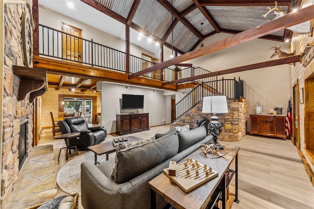 living room with beamed ceiling, a stone fireplace, high vaulted ceiling, and light hardwood / wood-style floors