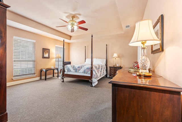 bedroom featuring dark carpet, a tray ceiling, and ceiling fan