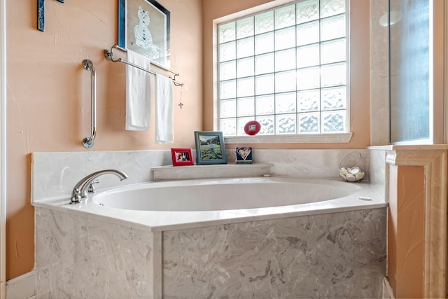 bathroom featuring tiled tub and a wealth of natural light