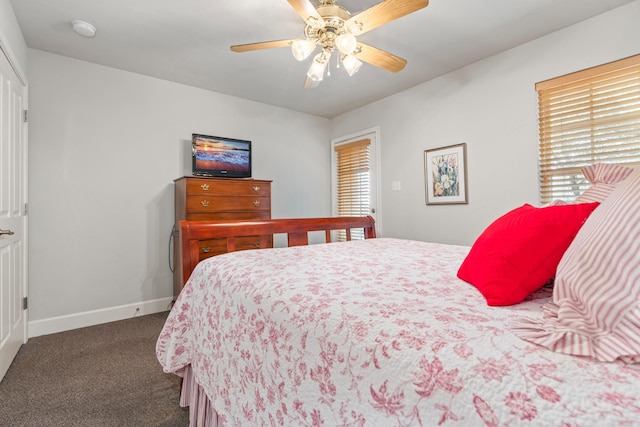 bedroom with ceiling fan, dark carpet, and multiple windows