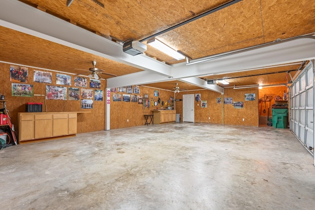 garage with a garage door opener, ceiling fan, and wooden walls