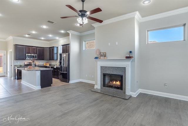 kitchen with dark brown cabinetry, appliances with stainless steel finishes, a kitchen island, and plenty of natural light