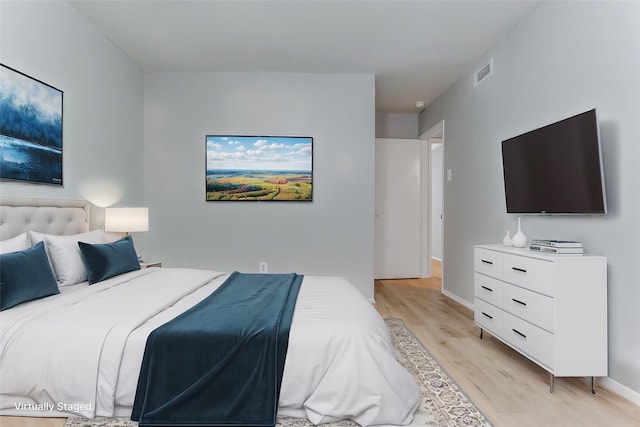 bedroom featuring baseboards, visible vents, and light wood finished floors