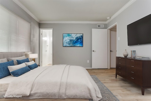 bedroom with crown molding, light wood-type flooring, and ensuite bath