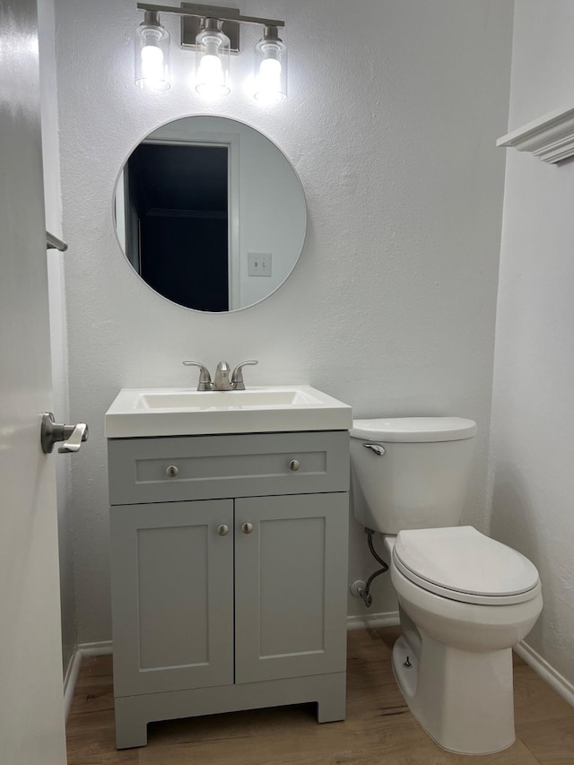 bathroom featuring baseboards, vanity, toilet, and wood finished floors