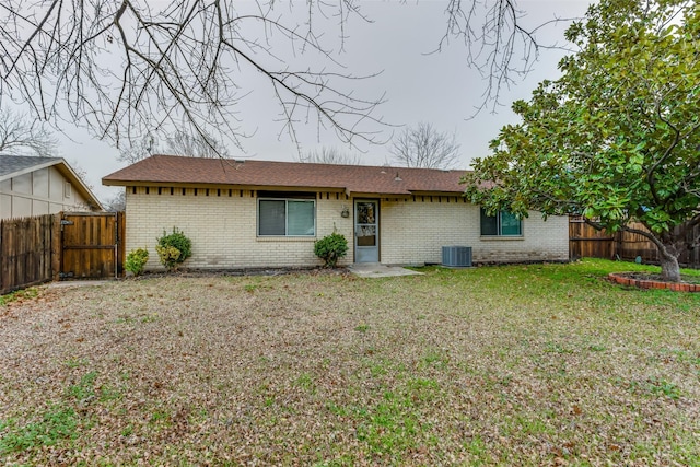 back of house with central AC unit, a fenced backyard, a gate, a yard, and brick siding