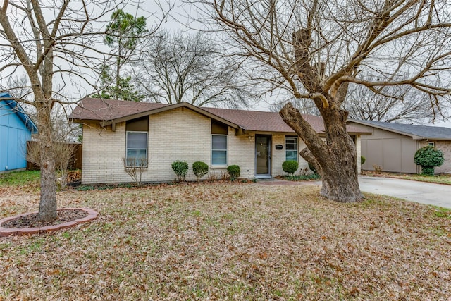 view of front facade featuring driveway, a front lawn, and brick siding