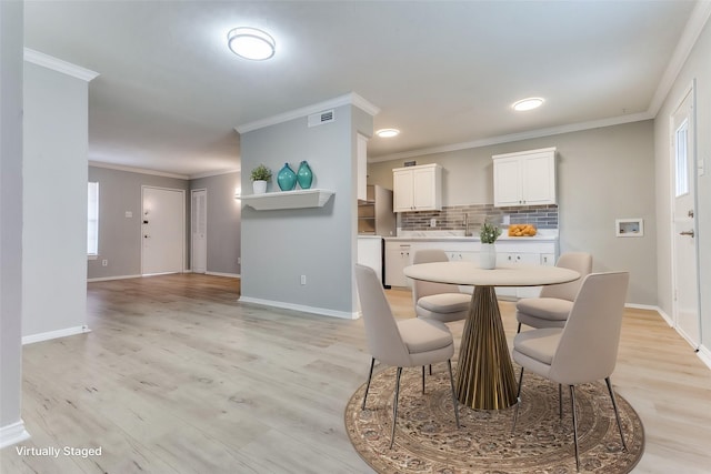 dining space featuring light wood finished floors, baseboards, visible vents, and ornamental molding