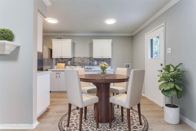 dining room with ornamental molding, light wood-style flooring, and baseboards