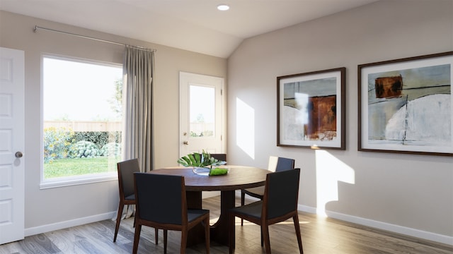 dining space with vaulted ceiling, light wood-type flooring, and baseboards