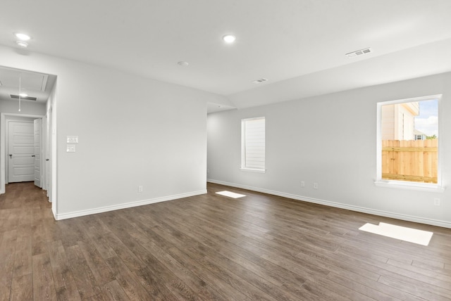 unfurnished room featuring recessed lighting, visible vents, baseboards, dark wood finished floors, and attic access