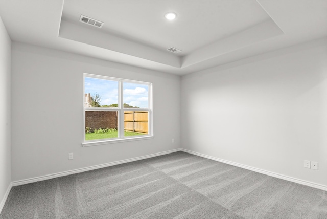 carpeted spare room with a tray ceiling, visible vents, baseboards, and recessed lighting