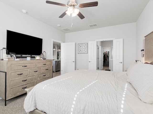 carpeted bedroom with a spacious closet, ceiling fan, and ensuite bathroom