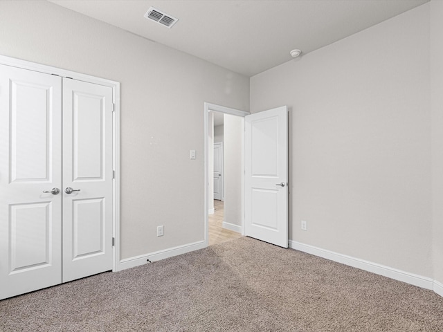 unfurnished bedroom featuring light colored carpet and a closet