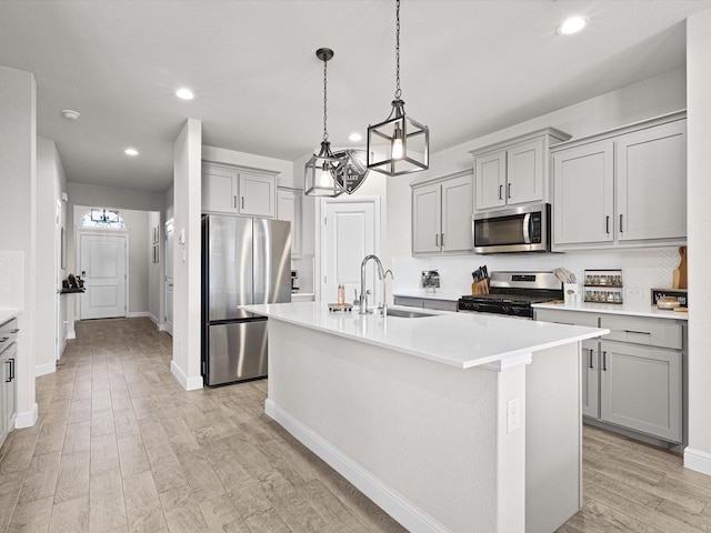 kitchen with sink, light hardwood / wood-style flooring, stainless steel appliances, and an island with sink