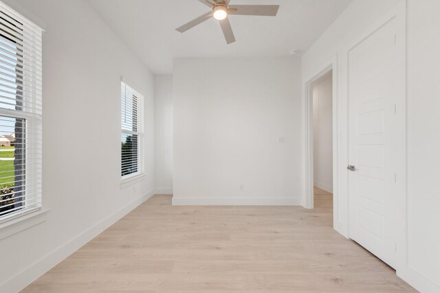 unfurnished room featuring ceiling fan, light wood-type flooring, baseboards, and a healthy amount of sunlight