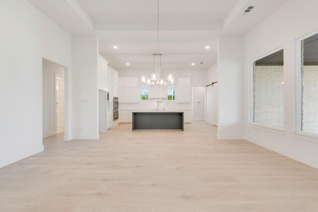 kitchen with open floor plan, light countertops, a chandelier, light wood-style floors, and white cabinetry