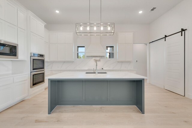 kitchen featuring stainless steel appliances, a barn door, light countertops, and white cabinetry