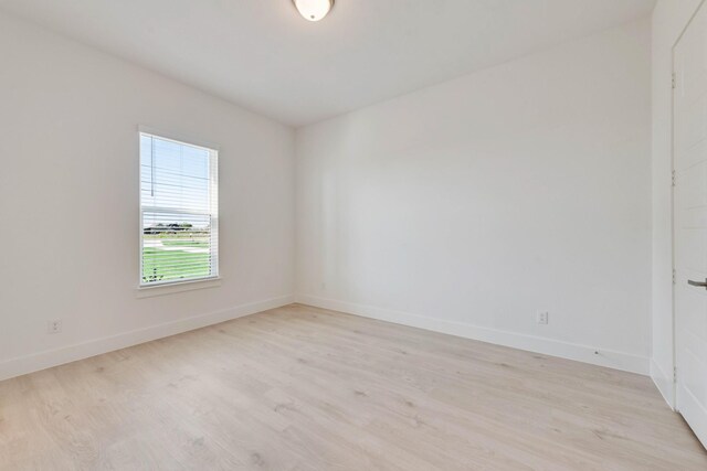 spare room featuring baseboards and light wood-style floors