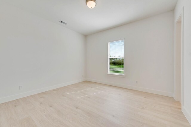 unfurnished room with visible vents, light wood-style flooring, and baseboards