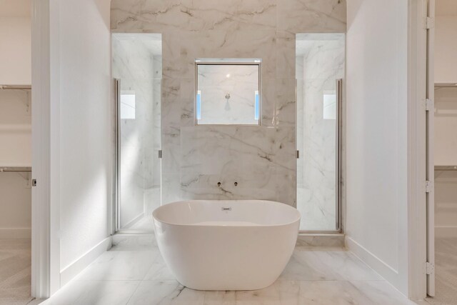bathroom with a freestanding bath, marble finish floor, a walk in closet, and a marble finish shower