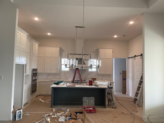 kitchen with a barn door, white cabinets, recessed lighting, and light countertops