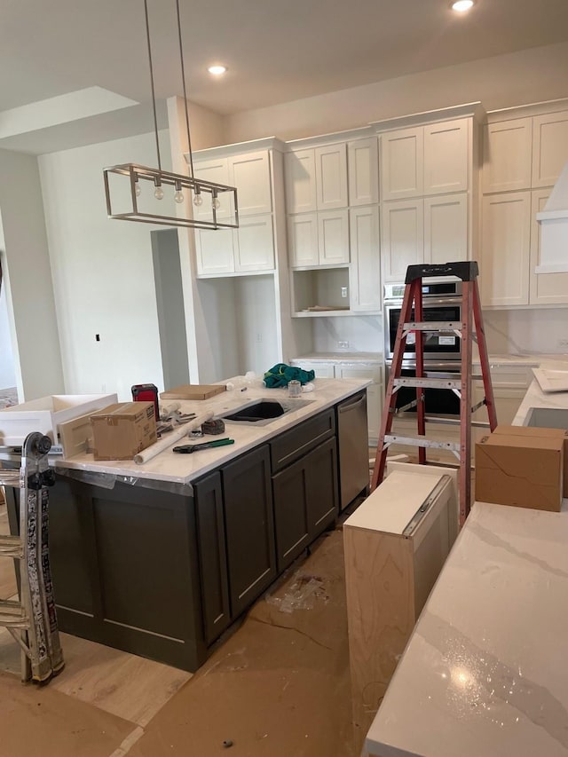 kitchen featuring a kitchen island, pendant lighting, white cabinets, stainless steel appliances, and a sink