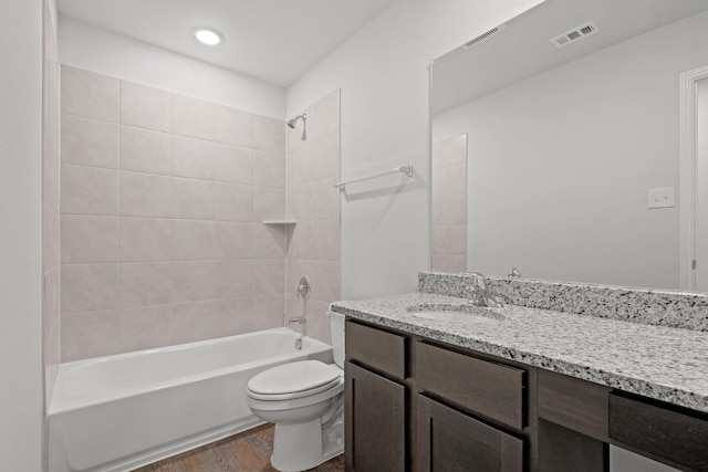 full bathroom featuring tiled shower / bath, vanity, toilet, and hardwood / wood-style floors