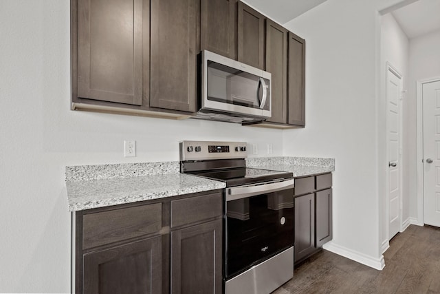 kitchen featuring dark brown cabinetry, appliances with stainless steel finishes, dark hardwood / wood-style flooring, and light stone countertops