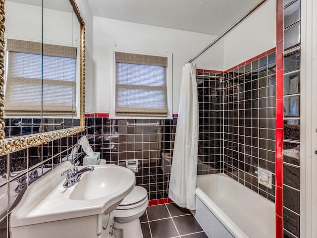 full bathroom with shower / tub combo with curtain, sink, tile walls, tile patterned flooring, and toilet