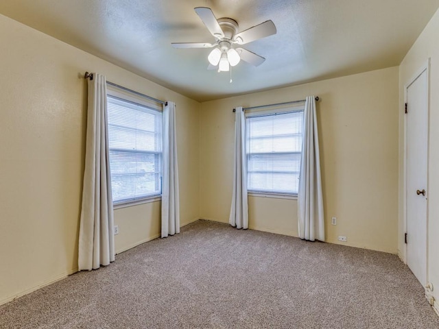 spare room with ceiling fan and light colored carpet