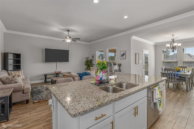 kitchen featuring pendant lighting, sink, white cabinetry, ornamental molding, and an island with sink