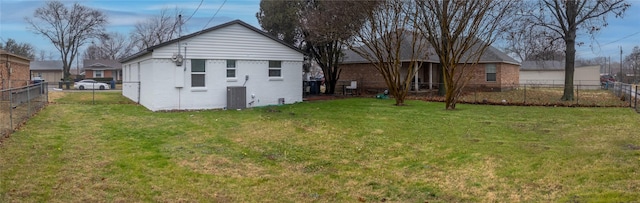 back of property with central AC unit and a yard