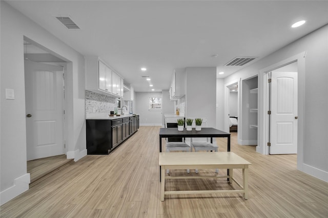 kitchen with dark brown cabinetry, sink, white cabinetry, light wood-type flooring, and decorative backsplash