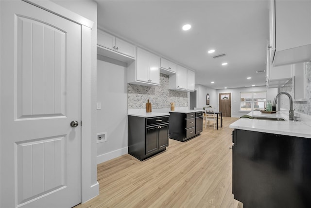 kitchen featuring white cabinetry, sink, backsplash, and light hardwood / wood-style flooring