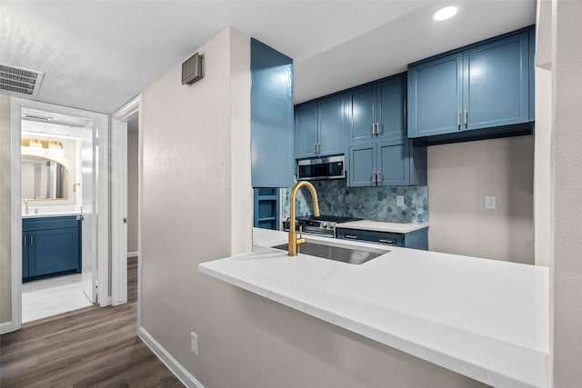 kitchen with sink, hardwood / wood-style flooring, blue cabinetry, and backsplash