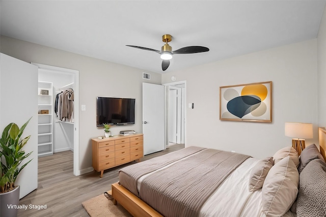 bedroom with a spacious closet, light hardwood / wood-style floors, a closet, and ceiling fan