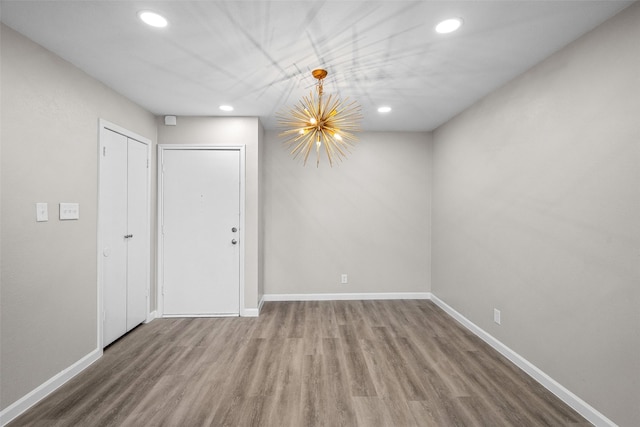 empty room featuring a notable chandelier and hardwood / wood-style flooring