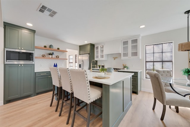 kitchen with white cabinetry, green cabinetry, a kitchen bar, built in microwave, and stainless steel fridge with ice dispenser